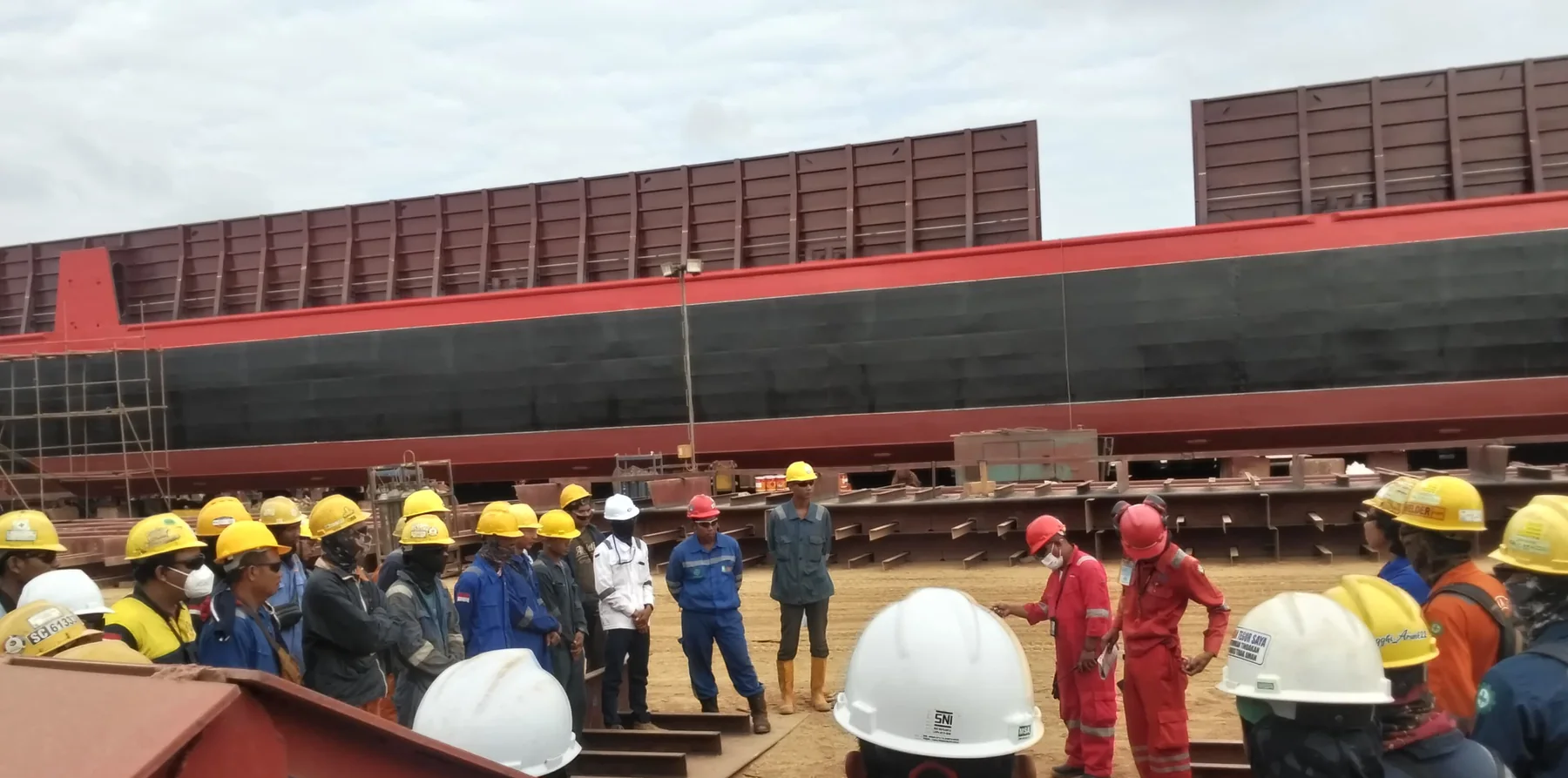 Rivesa yard briefing beside barge hull